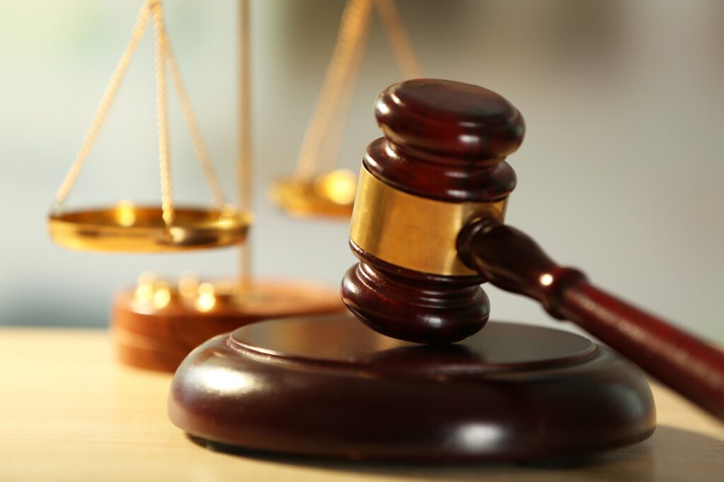 A gavel resting on its stand in front of scales of justice.