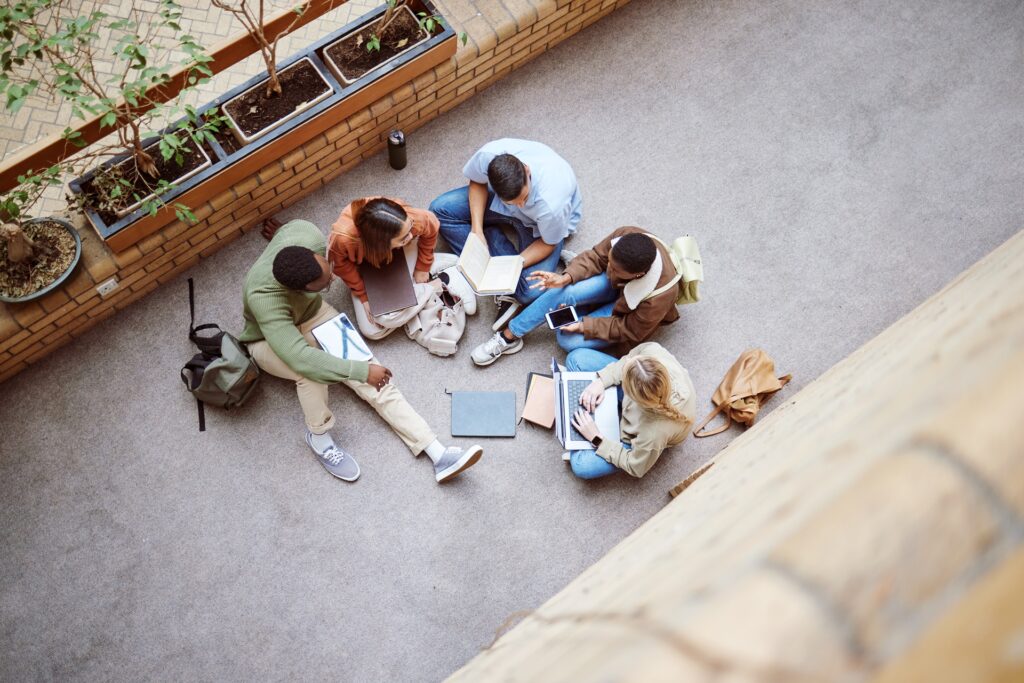 An overhead view of a group of kids studying outside on the ground.